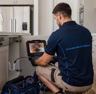 Plumber clearing a blocked toilet in a Mona Vale bathroom